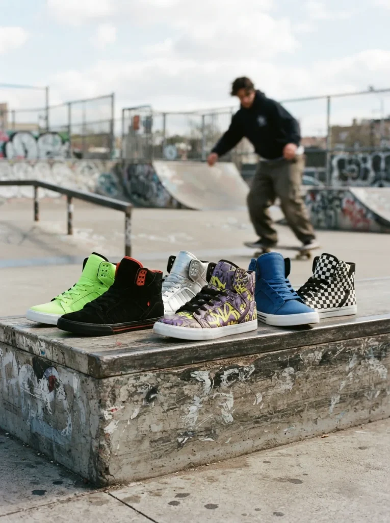 Supra Skytop shoes displayed in a skate culture setting with a skateboarder in the background.